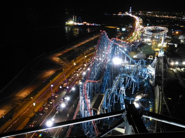 Photo of Blackpool Pleasure Beach and the Blackpool seafront from the top of the Big One, at night with the park illuminated and the Blackpool Illuminations switched on.